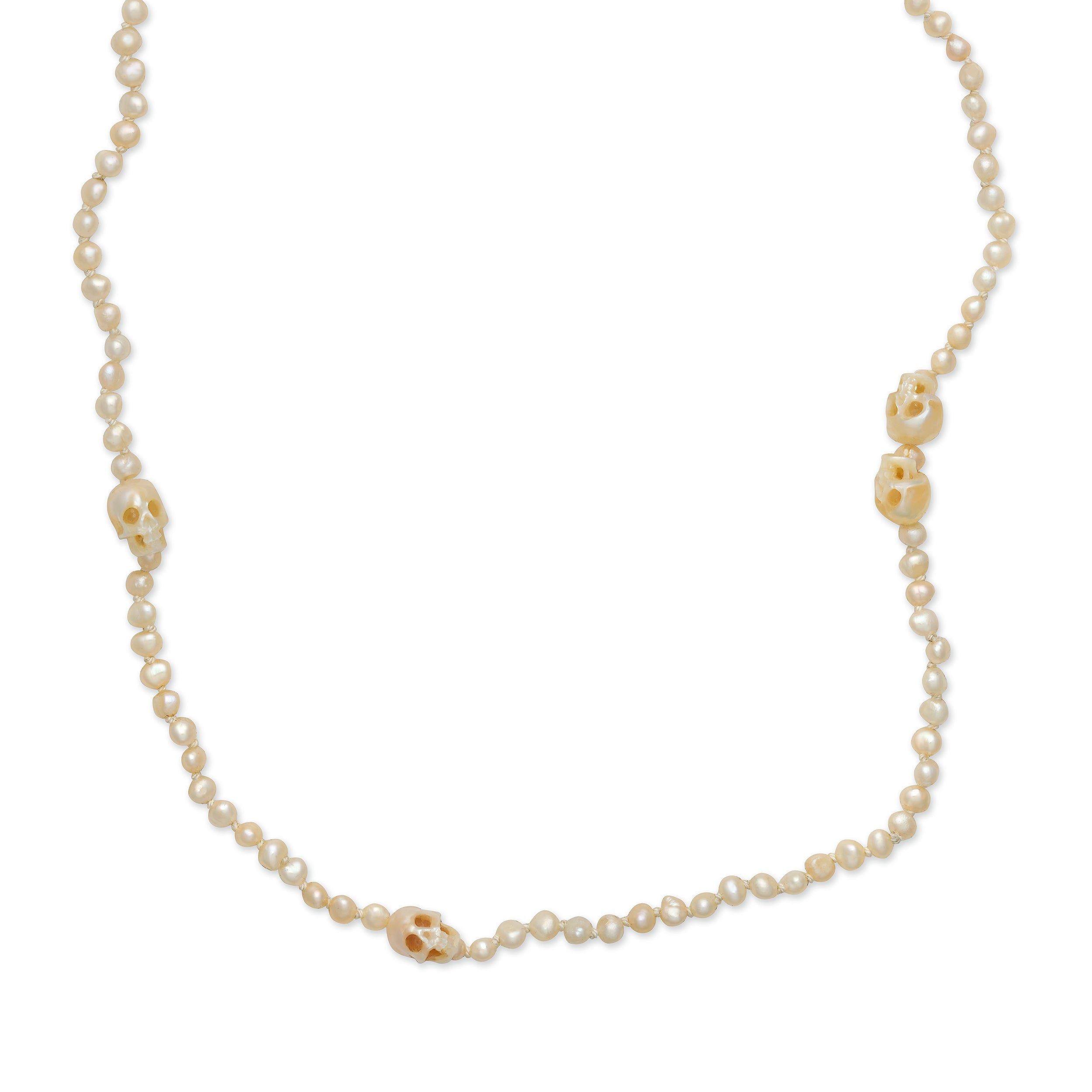 A white pearl necklace with hand-carved pearl skulls and a silk thread finish designed by Maura Green.