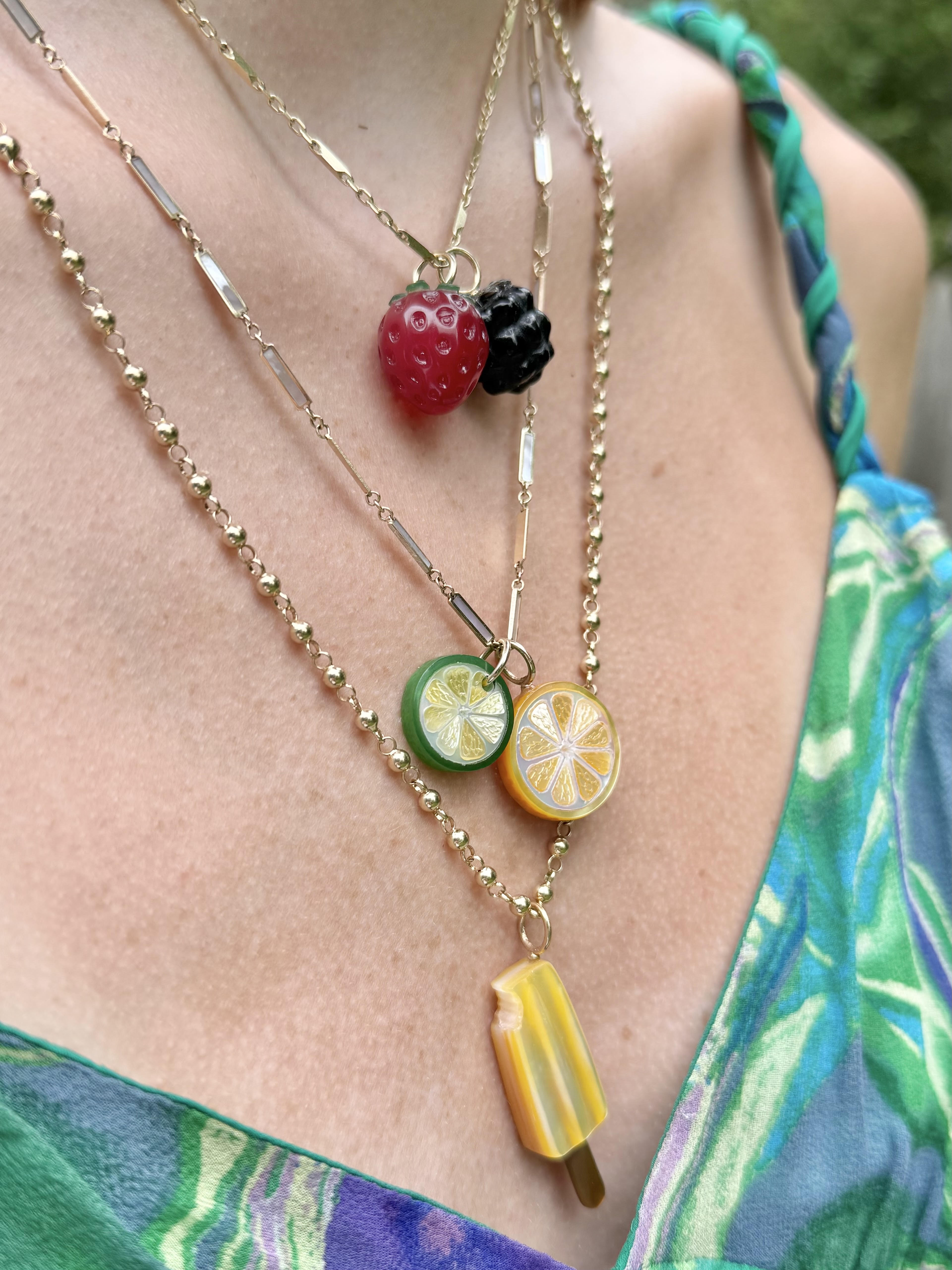 Necklace stack worn by model featuring the popsicle charm on a gold chain. Designed by Maura Green