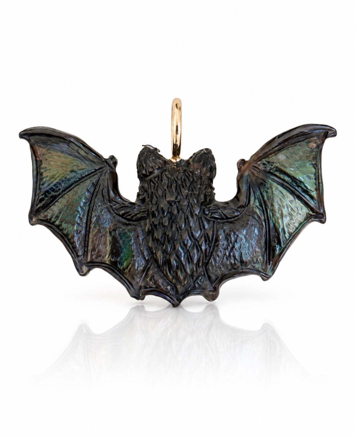 Back view of the Maura Green hand-carved black pinna shell bat charm, featuring outstretched wings with intricate carved detailing and natural iridescent flashes of green, blue, and violet. A textured body and polished 14K yellow gold bail complete the charm, photographed against a white background with a soft reflection.