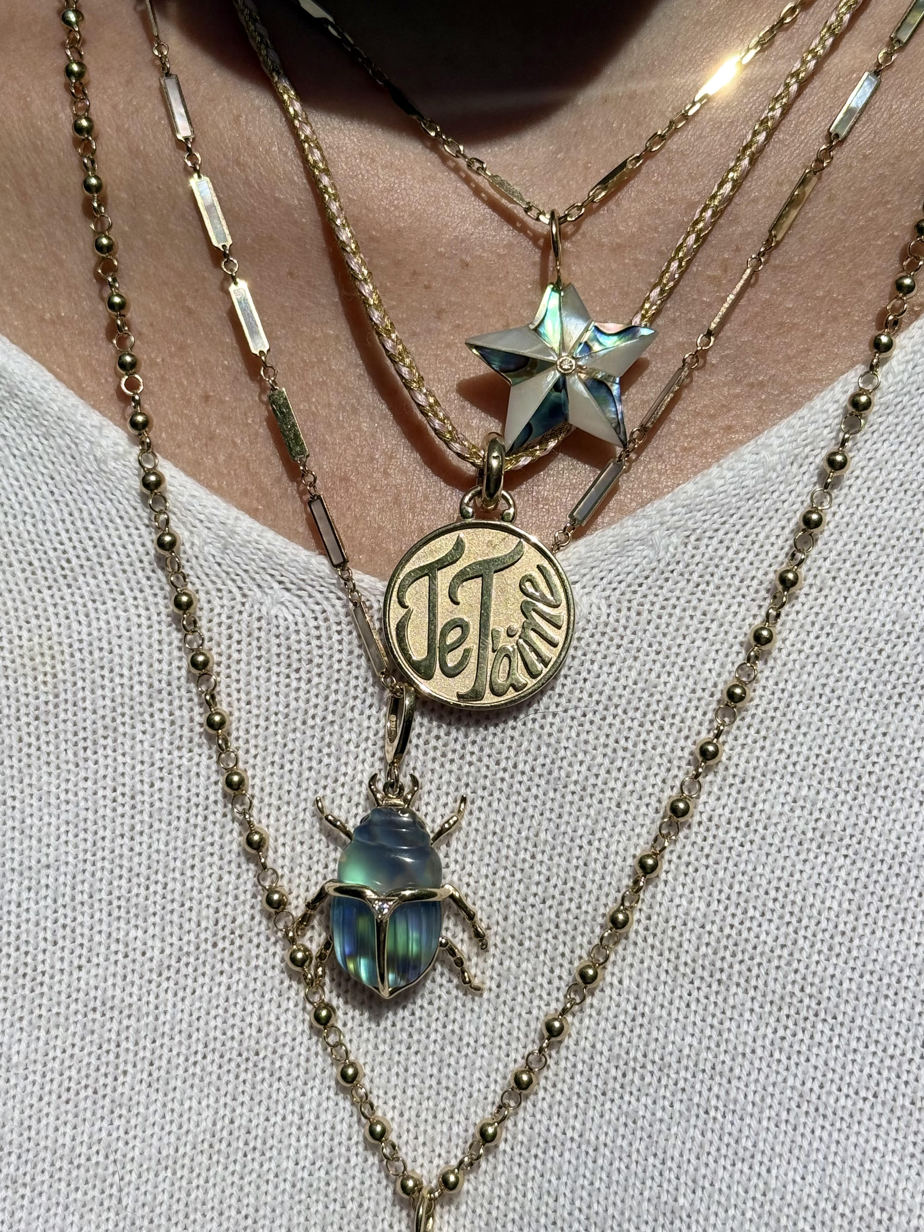 Necklace stack featuring Beveled Luminescent Star charm on a gold chain. Designed by Maura Green
