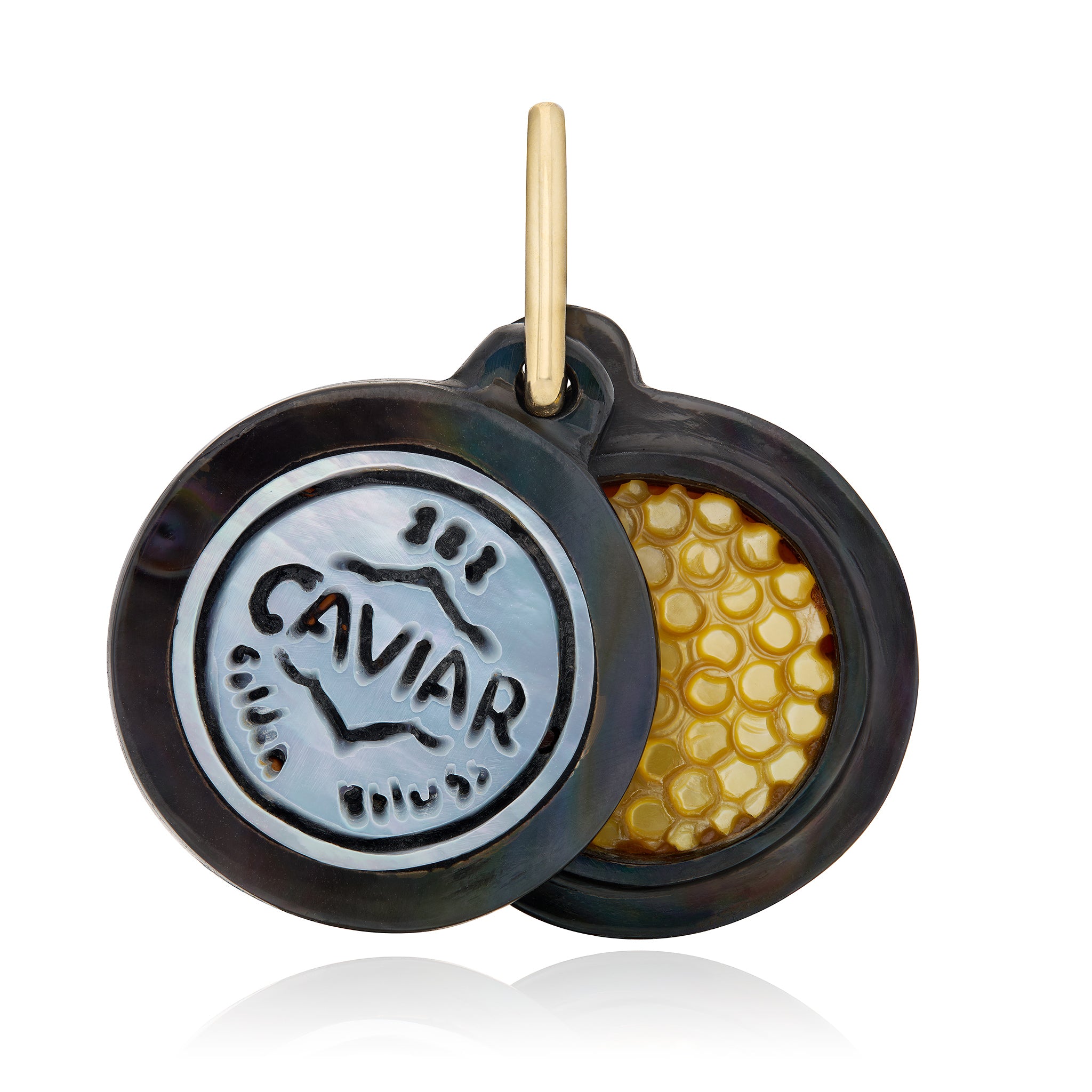 A round caviar-themed pendant or charm with a hinged lid design. One side features a silver-toned circular emblem engraved with 'CAVIAR,' while the other side reveals a textured golden-yellow caviar bead pattern inside. Designed by Maura Green Jewelry