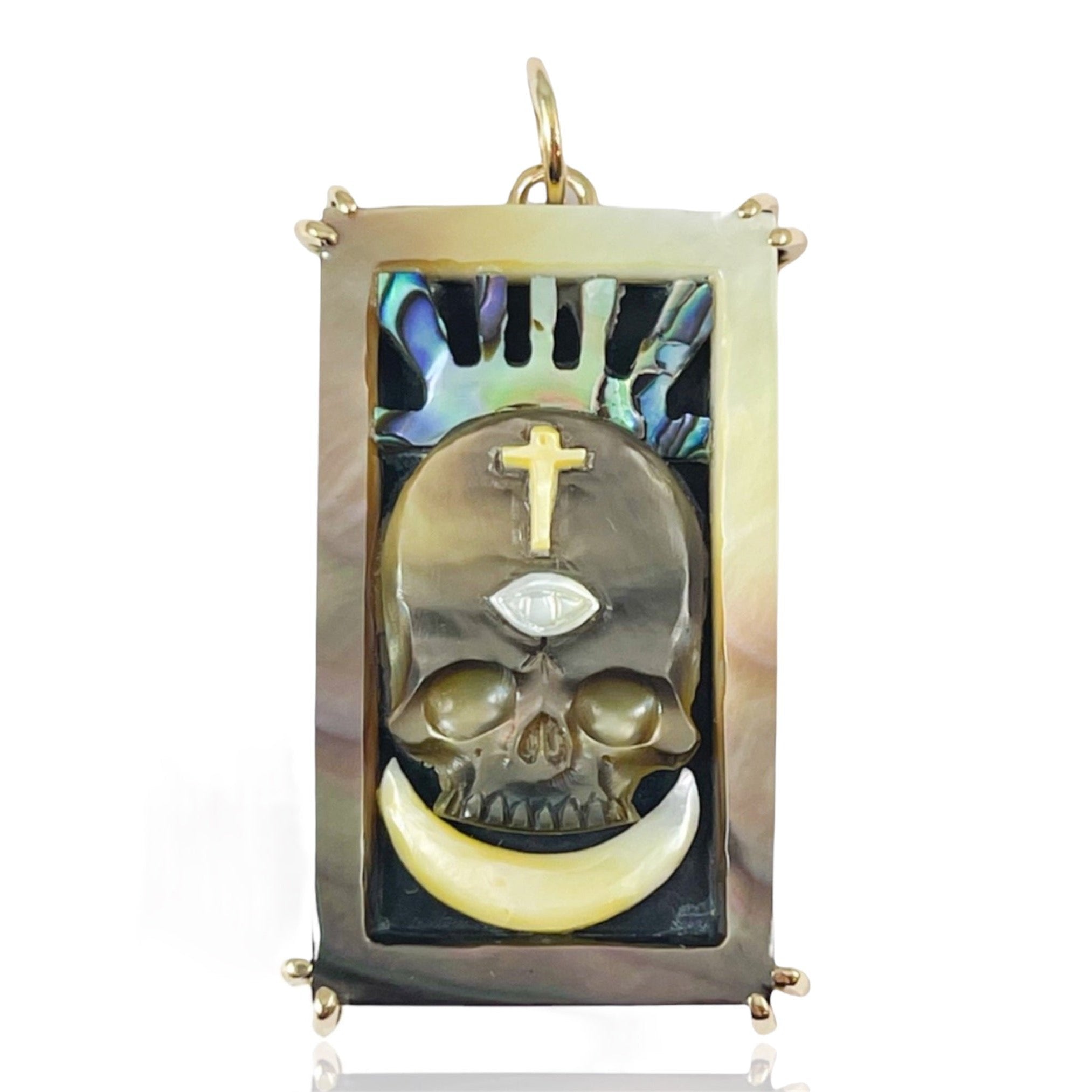 A hand carved brown mother of pearl rectangular shaped charm depicting a skull and a crescent moon, representing the death tarot card against a white background