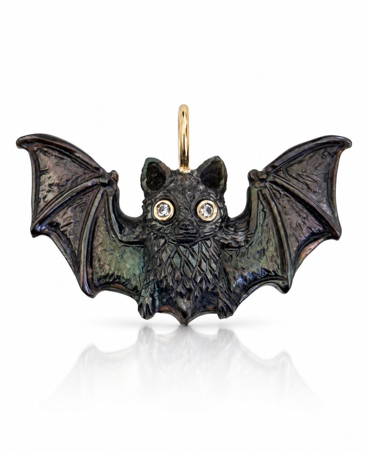 Hand-carved black pinna shell gothic style bat charm with outstretched, intricately carved wings, two round diamond eyes set in 14K yellow gold, and a polished gold bail. The iridescent shell reveals subtle green, blue, and purple tones. Photographed against a white background with a soft reflection.