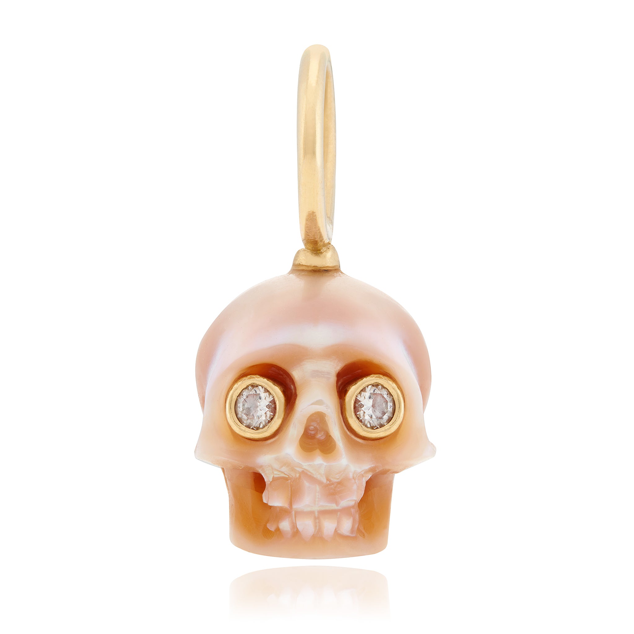 A hand-carved freshwater pearl skull charm with eyes inset with diamonds, attached to a gold bale designed by Maura Green.