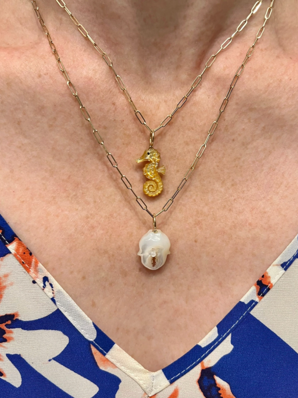 Gold seahorse charm on gold chain being worn by model. Designed by Maura Green