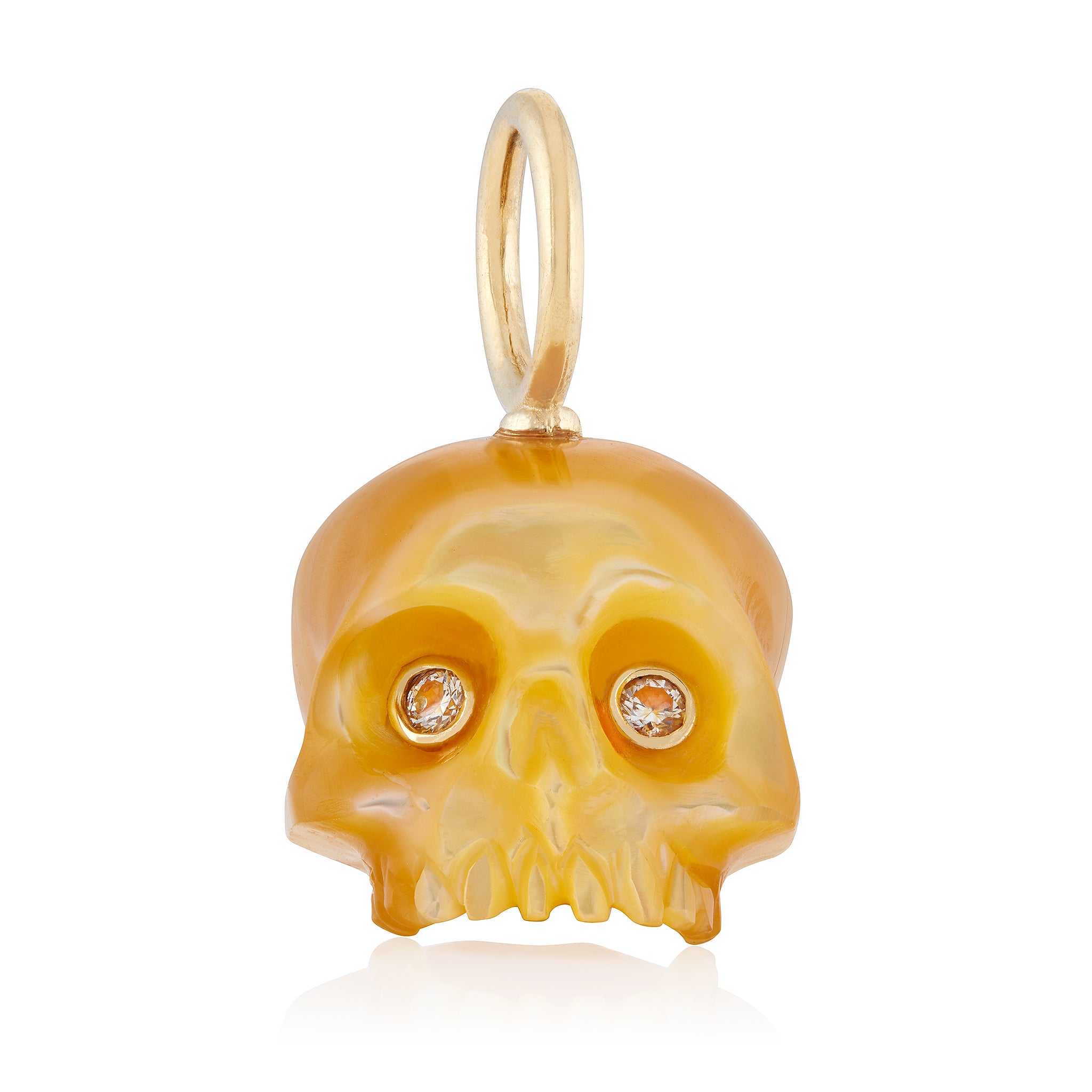A hand-carved golden mother of pearl skull charm with 14K gold bale and diamond eyes set in 14K yellow gold bezels designed by Maura Green