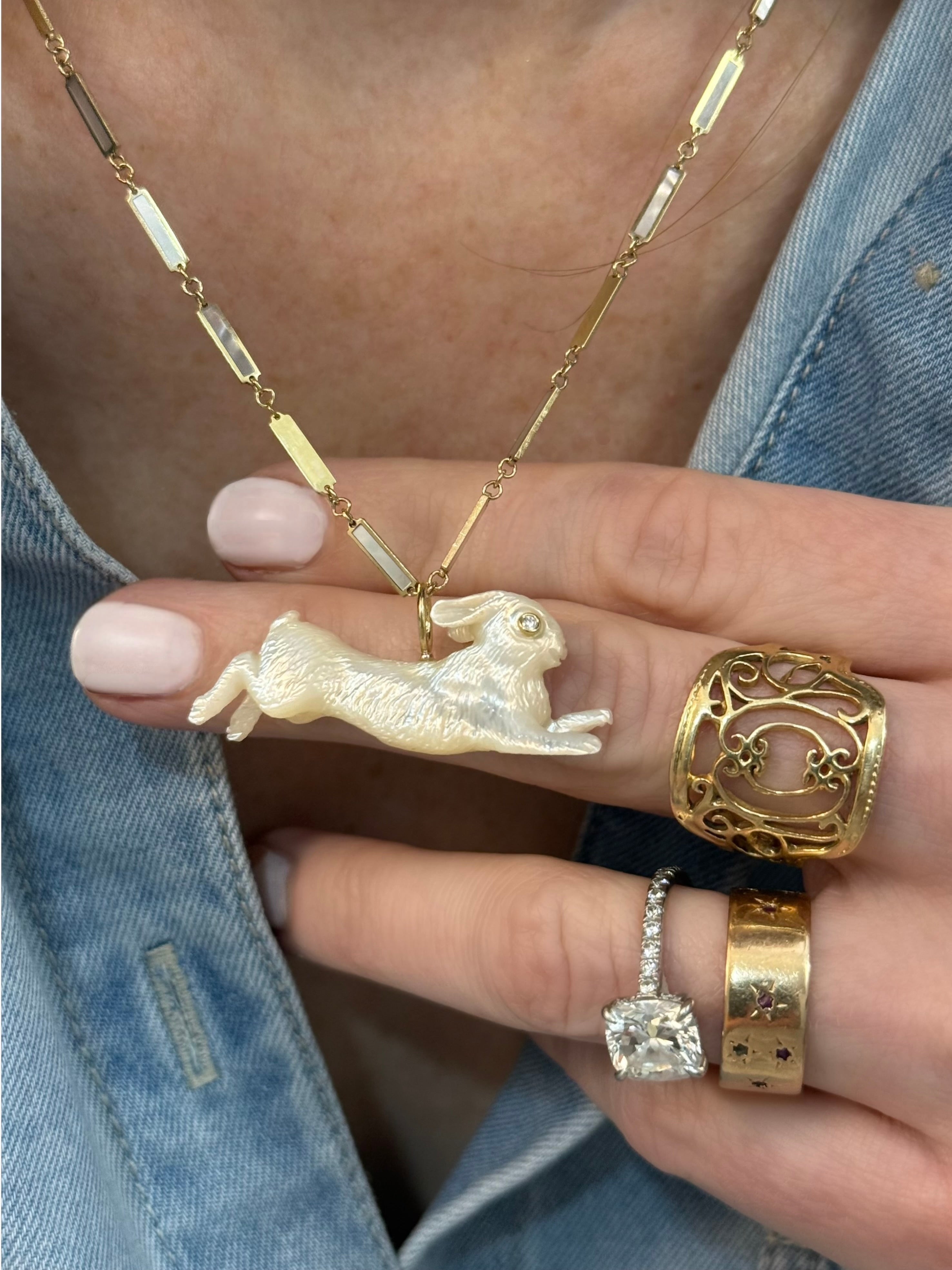 Gold necklace with a rabbit pendant worn on model's neck. Designed by Maura Green