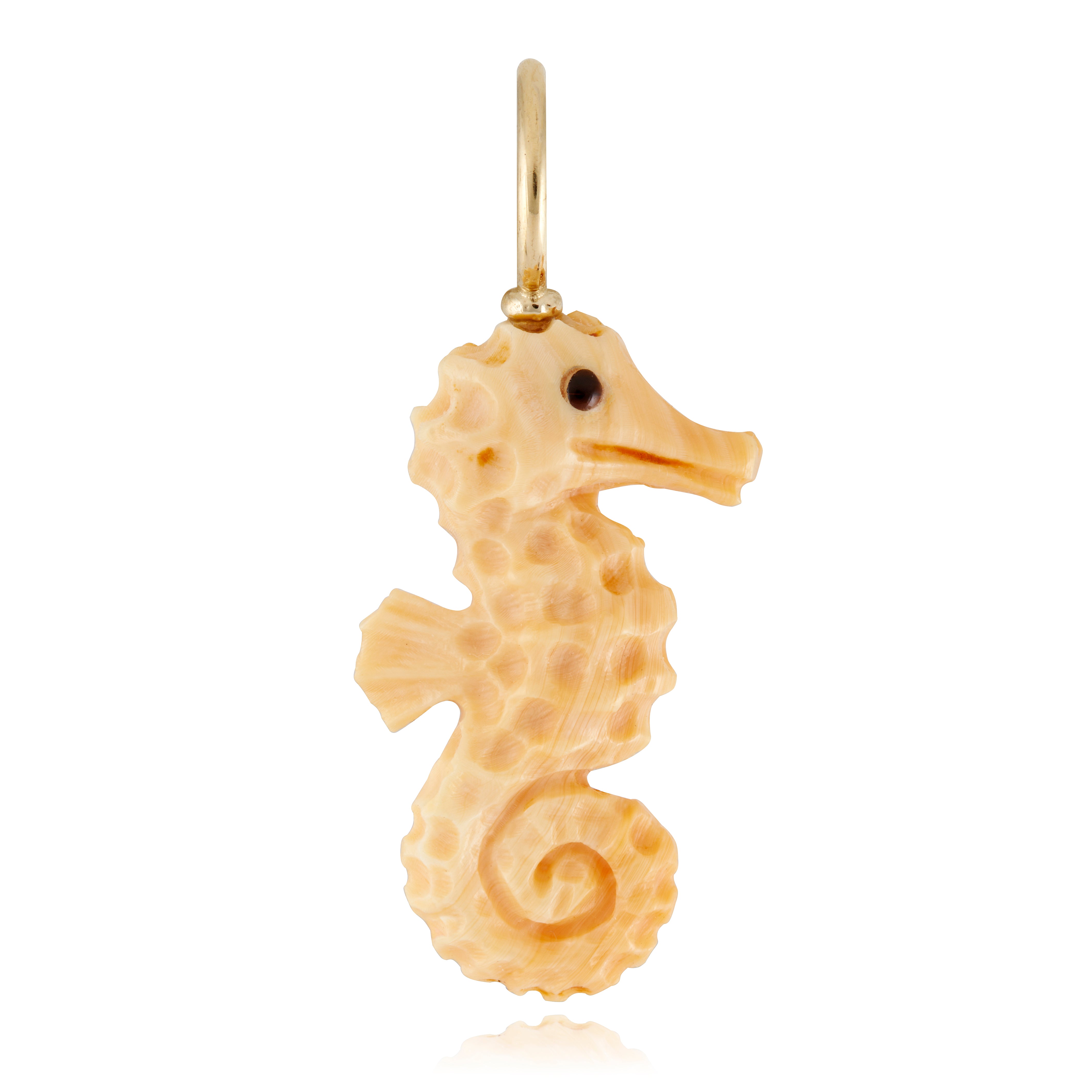 A gold-colored seahorse charm made from apricot conch shell against a white background designed by Maura Green.