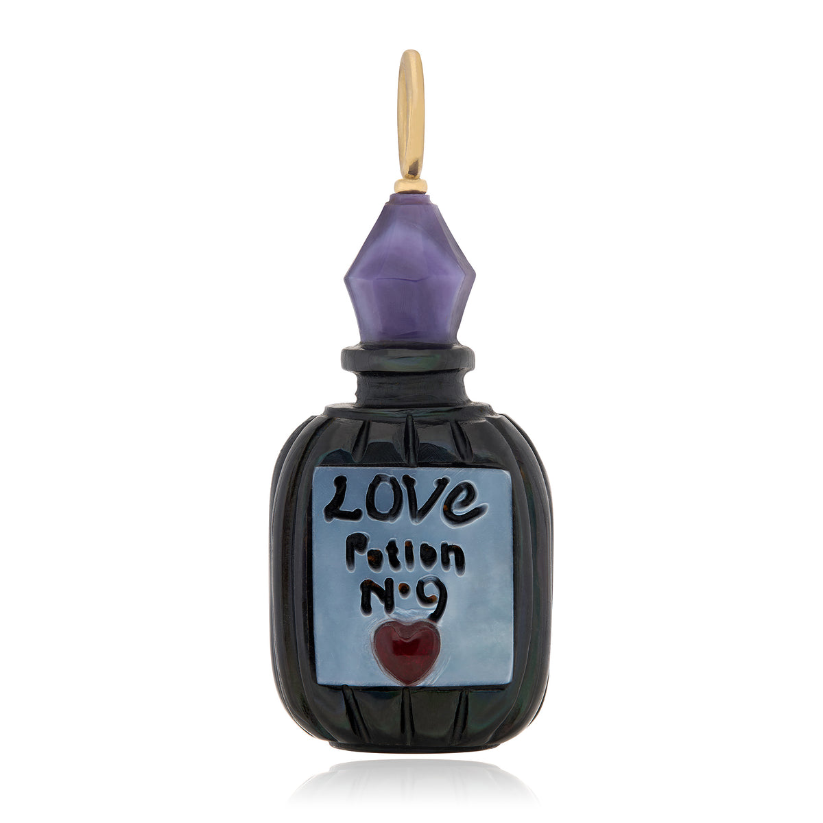 A decorative charm carved from black and purple shell to resemble an antique apothecary bottle with 14K yellow gold bail at the top on a white background. The label on the bottle is blueish white and reads "Love Potion no 9" and features a small red chalcedony carved heart. Designed by Maura Green.