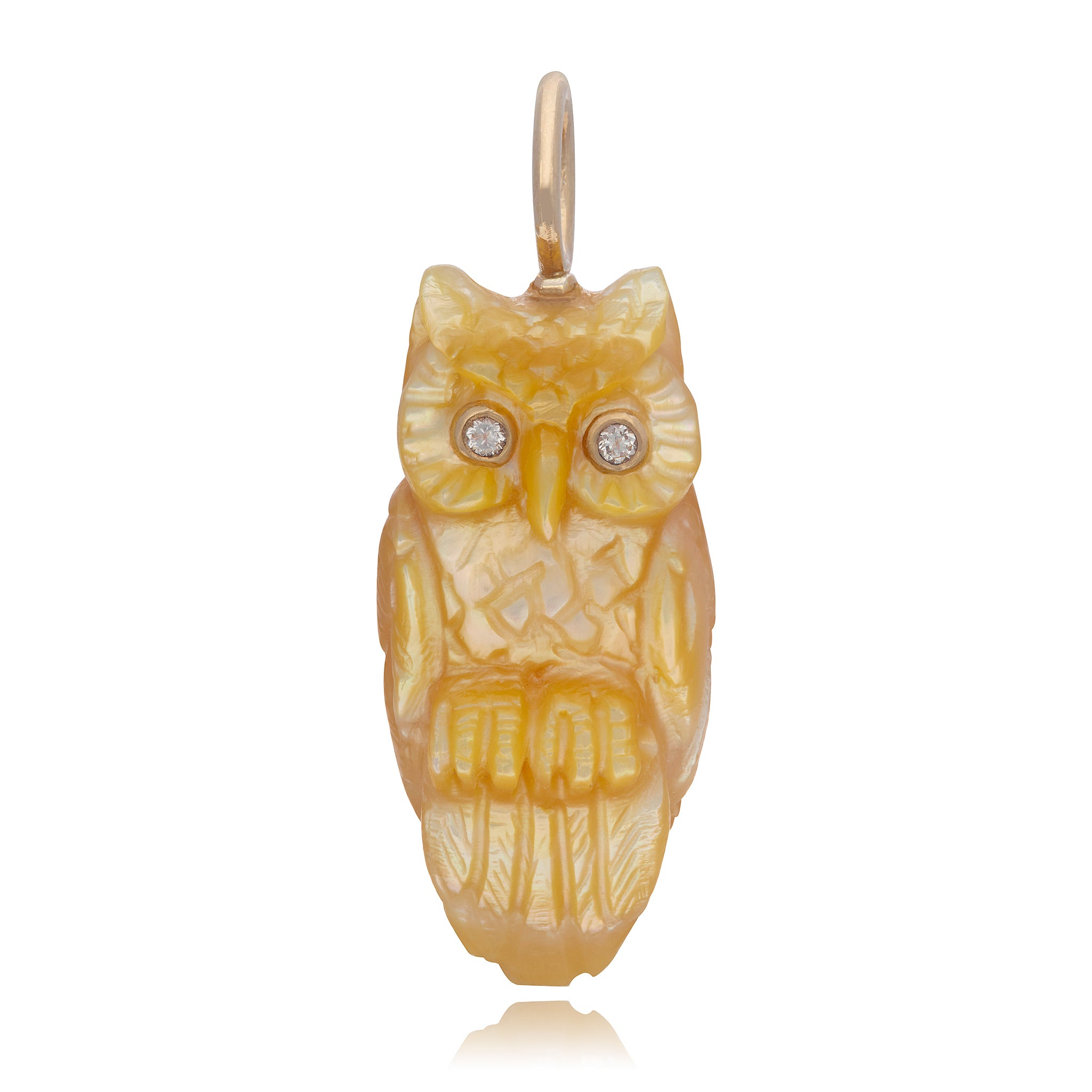 A 3D carved gold mother of pearl owl designed by Maura Green, with diamond eyes, suspended from a gold chain in front of a white background.