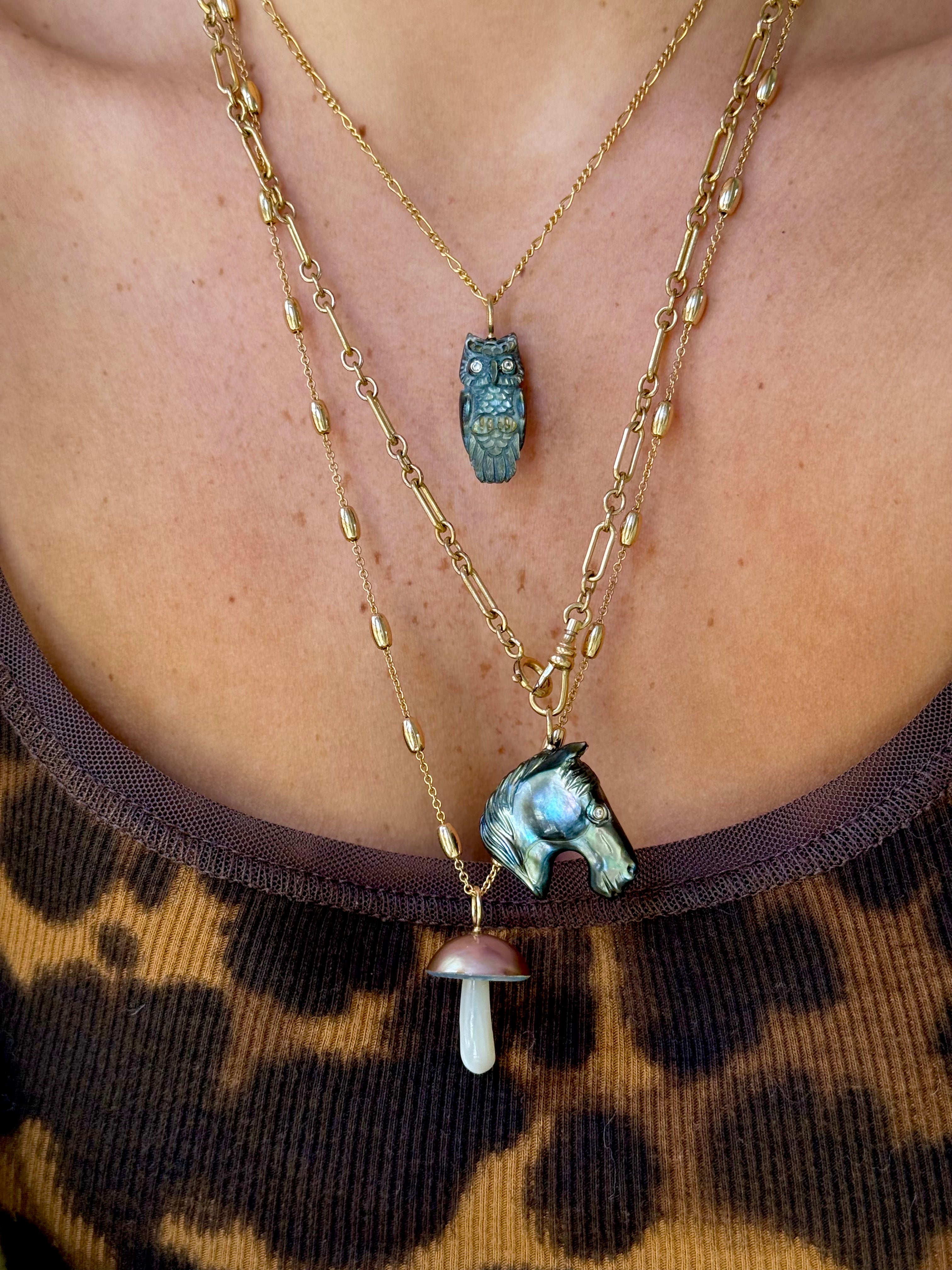 Close-up of layered necklaces with nature-themed pendants on a leopard print background