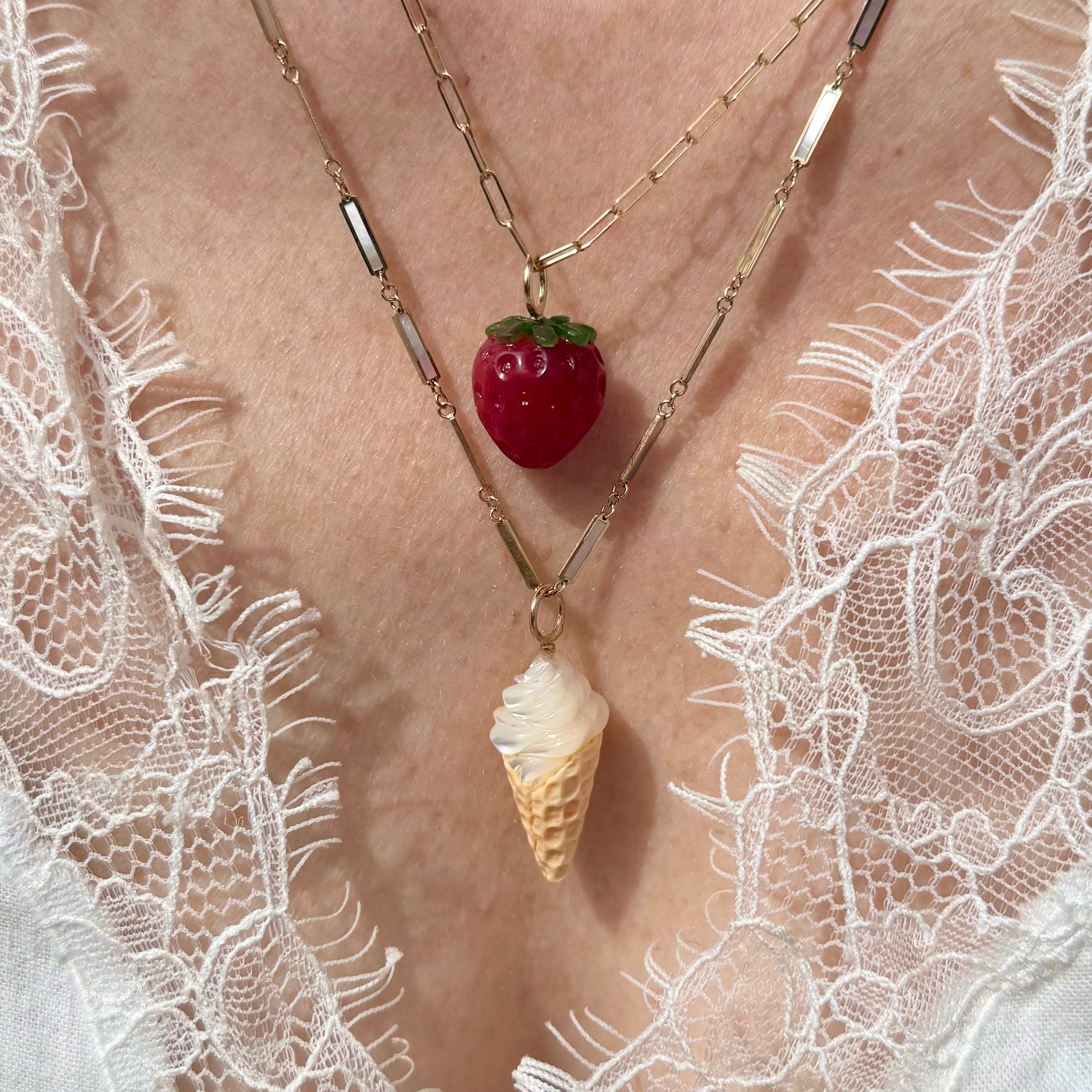 Necklace with strawberry and ice cream cone pendant on a lace garment designed by maura green