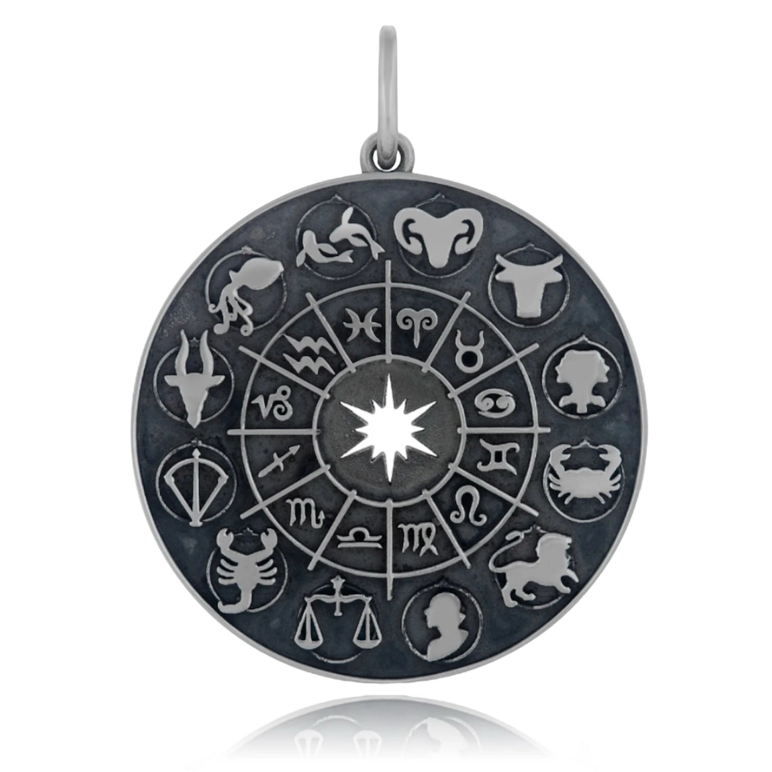 A blackened sterling silver zodiac wheel charm pendant designed by Maura Green, featuring 12 astrological signs around the perimeter and an open starburst symbol at the charm's center, against a white background.