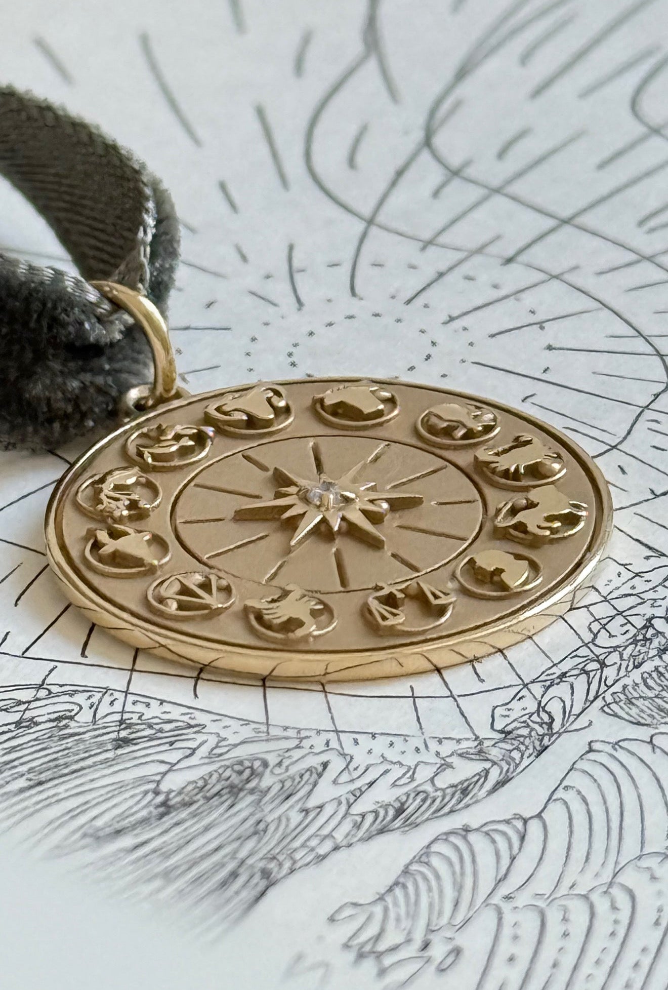Gold zodiac wheel pendant on a map background by Maura Green jewelry
