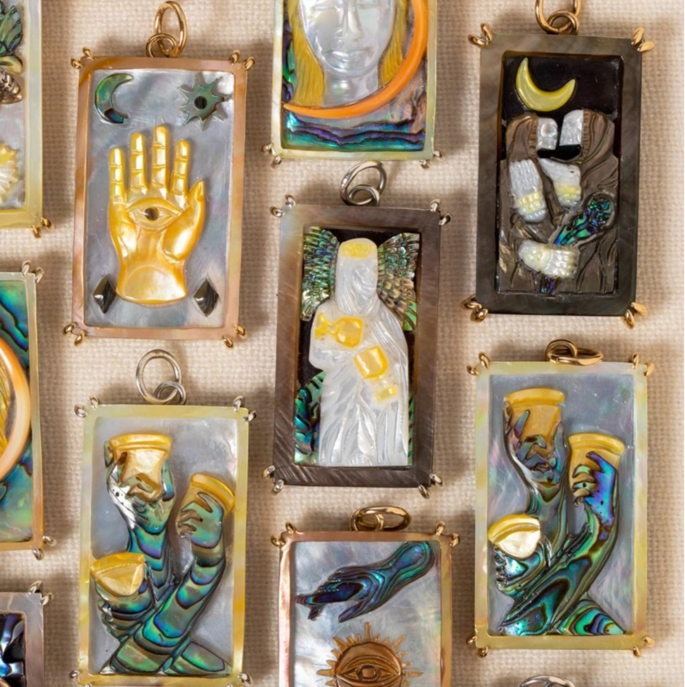 Flay lay image of several  colorful, rectangular hand carved charms depicting images from various tarot cards.