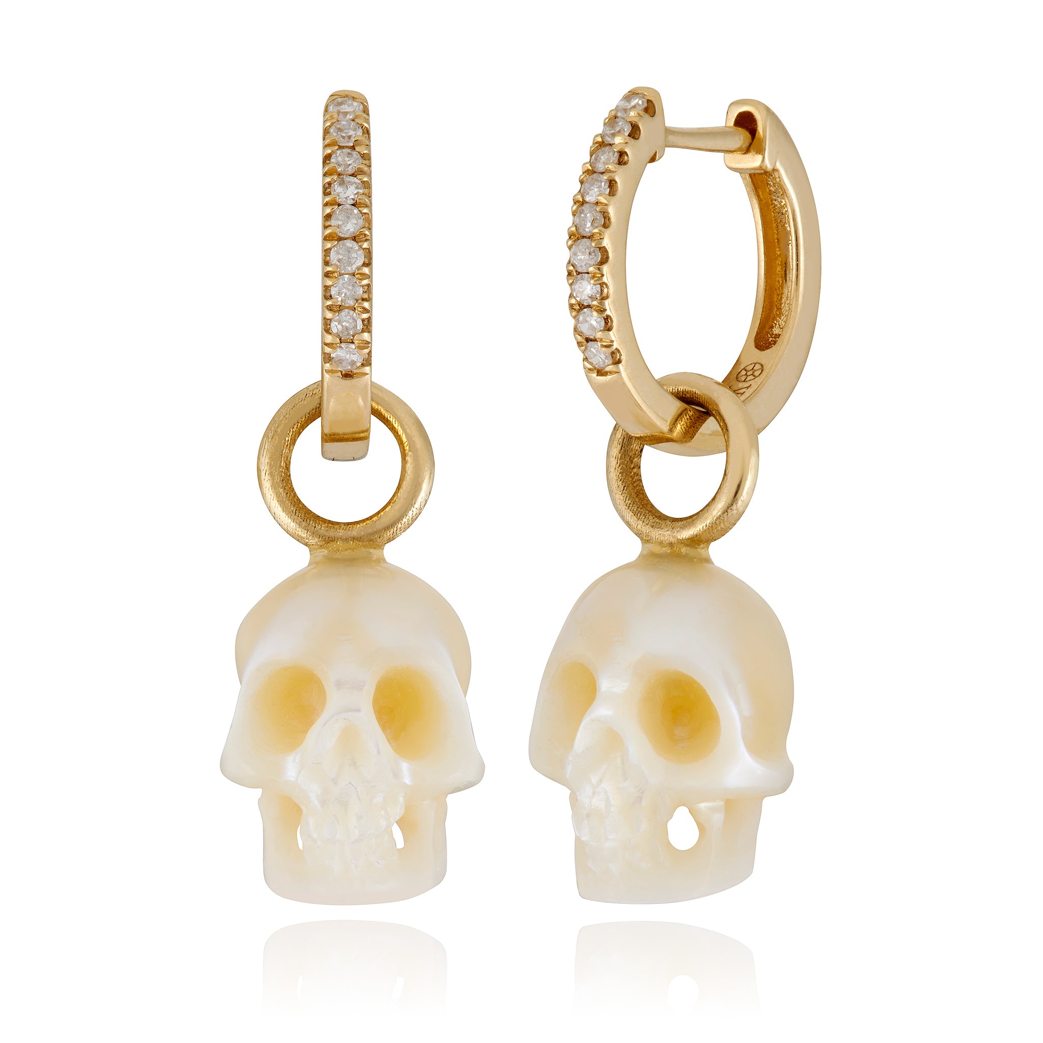 A pair of Maura Green Jewelry earrings featuring hand-carved pearl skulls with diamond and gold huggies.