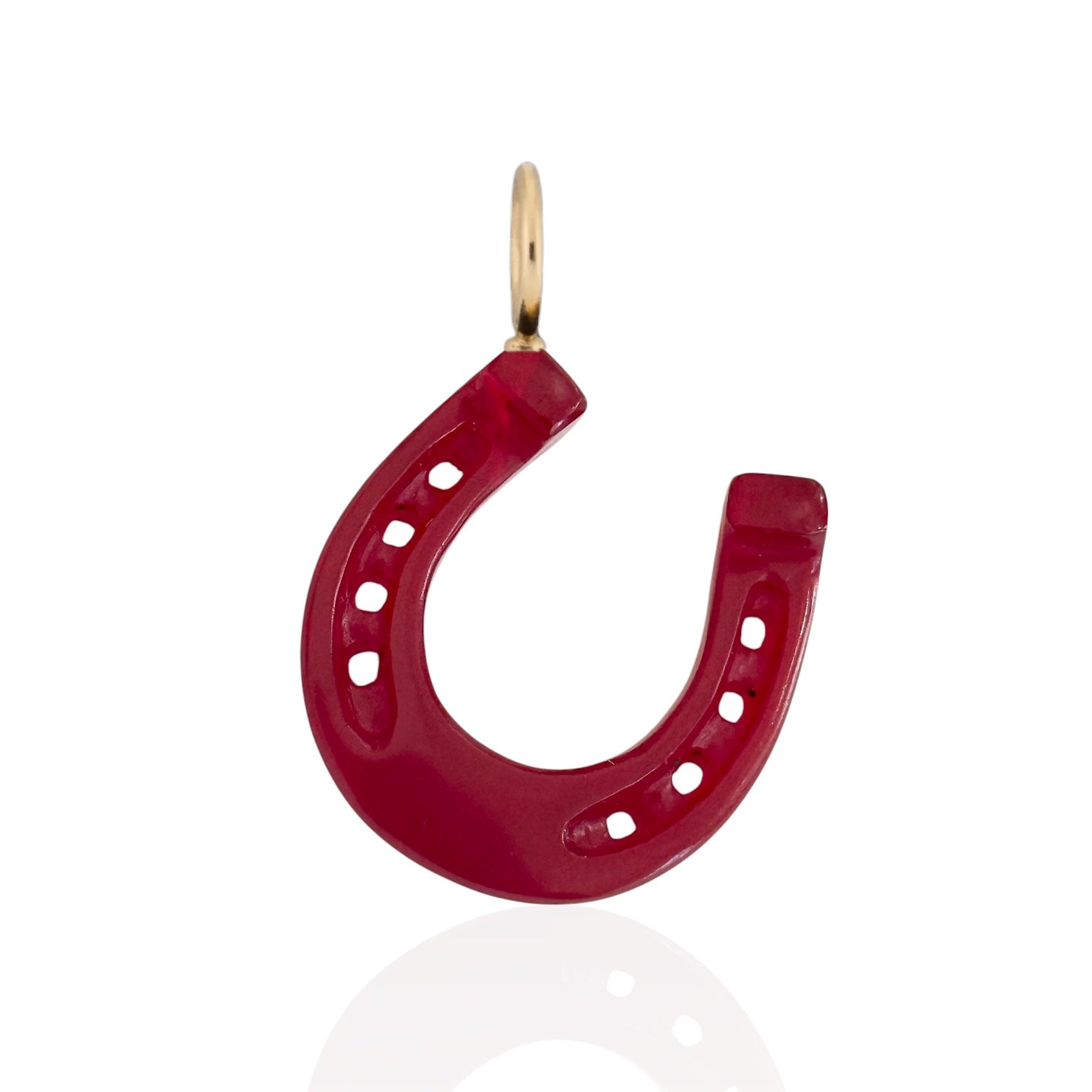 A red horseshoe-shaped charm pendant with a gold bail, shown on a clean white background with a subtle reflection below.