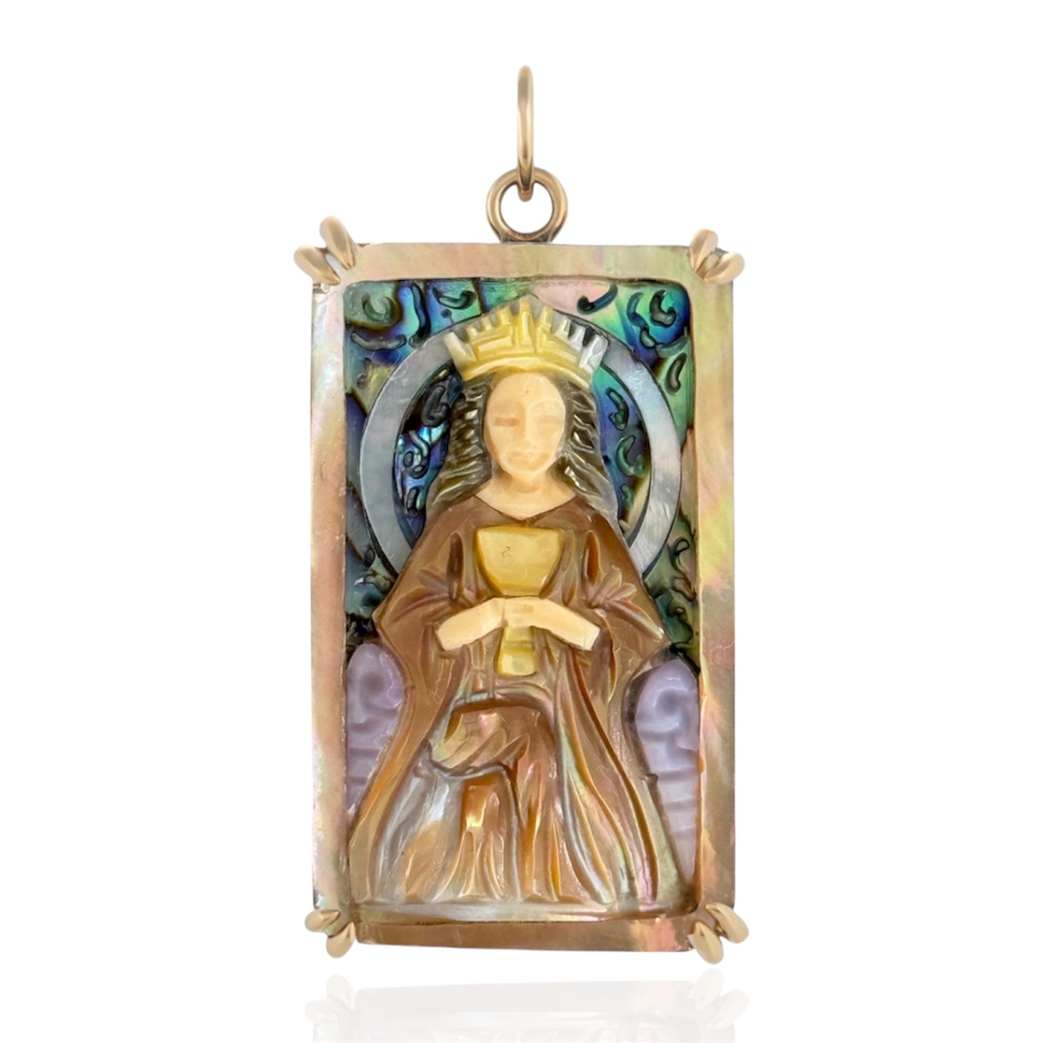 Rectangular pendant cham depicting a robed woman on seated a throne holding a chalice on a white background. Yellow gold setting and the charm is hand carved from colorful shells. Designed by Maura Green.