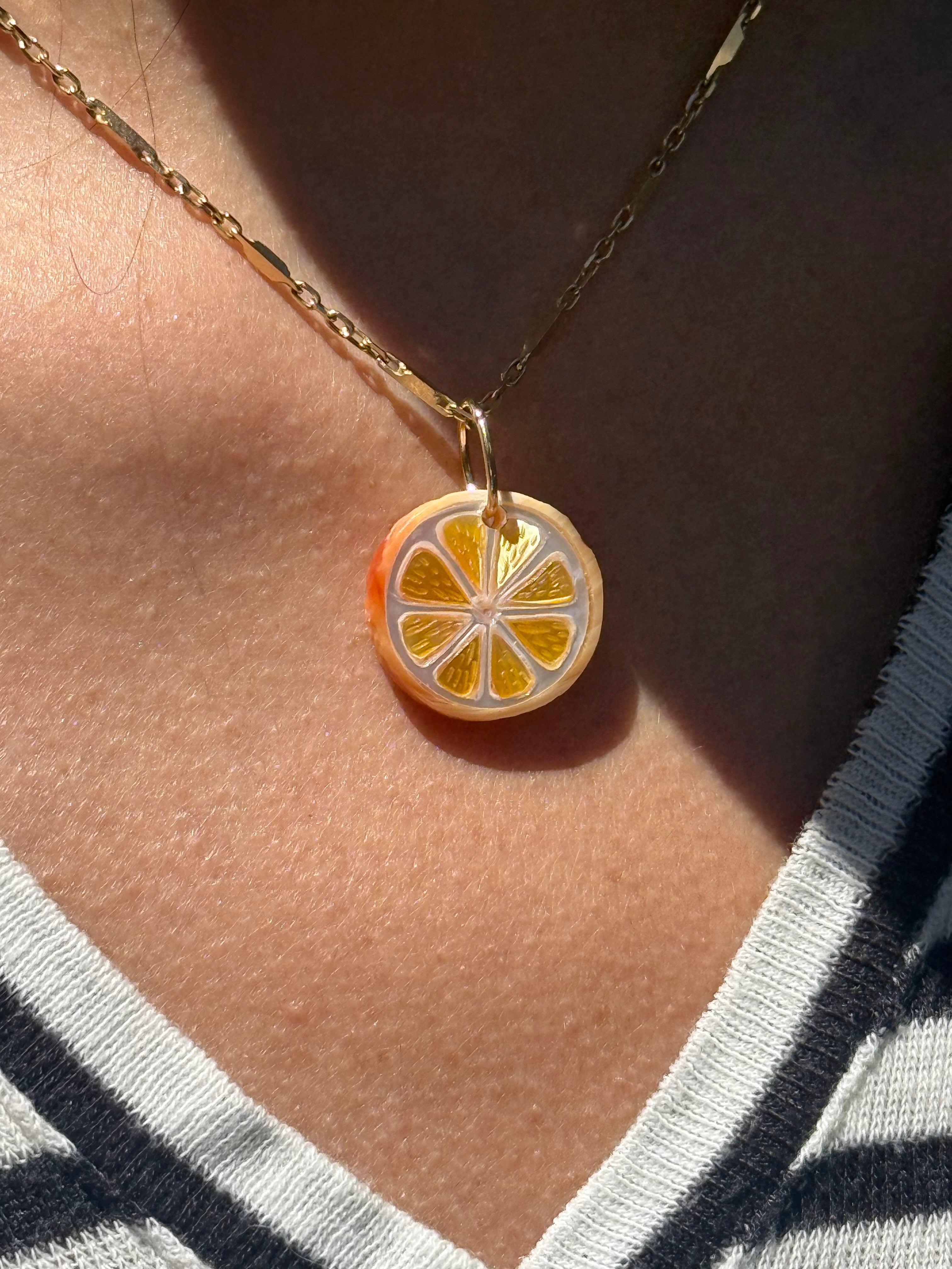 Necklace with an orange slice pendant on a model's neck. Designed by Maura Green