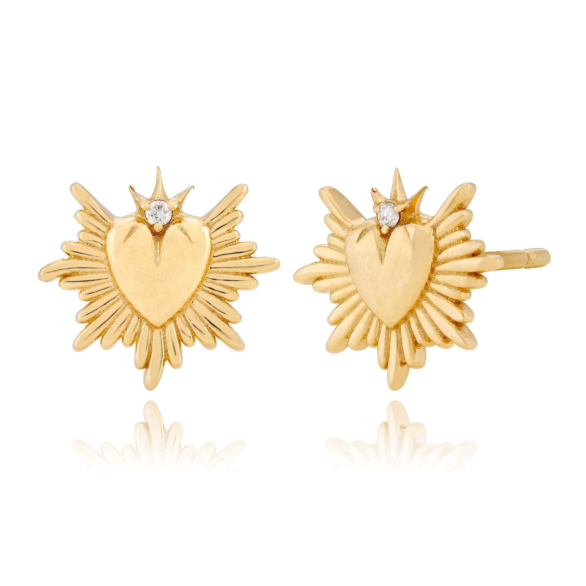 Gold heart-shaped earrings with starburst design and a diamond on the top on a white background designed by maura green