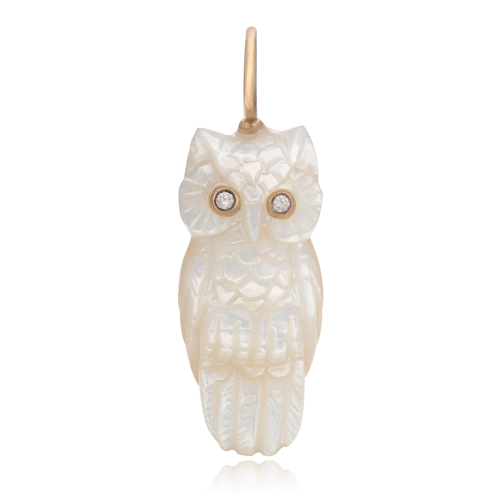 A 3D carved white mother of pearl owl with 14K solid gold and diamond eyes, designed by Maura Green.