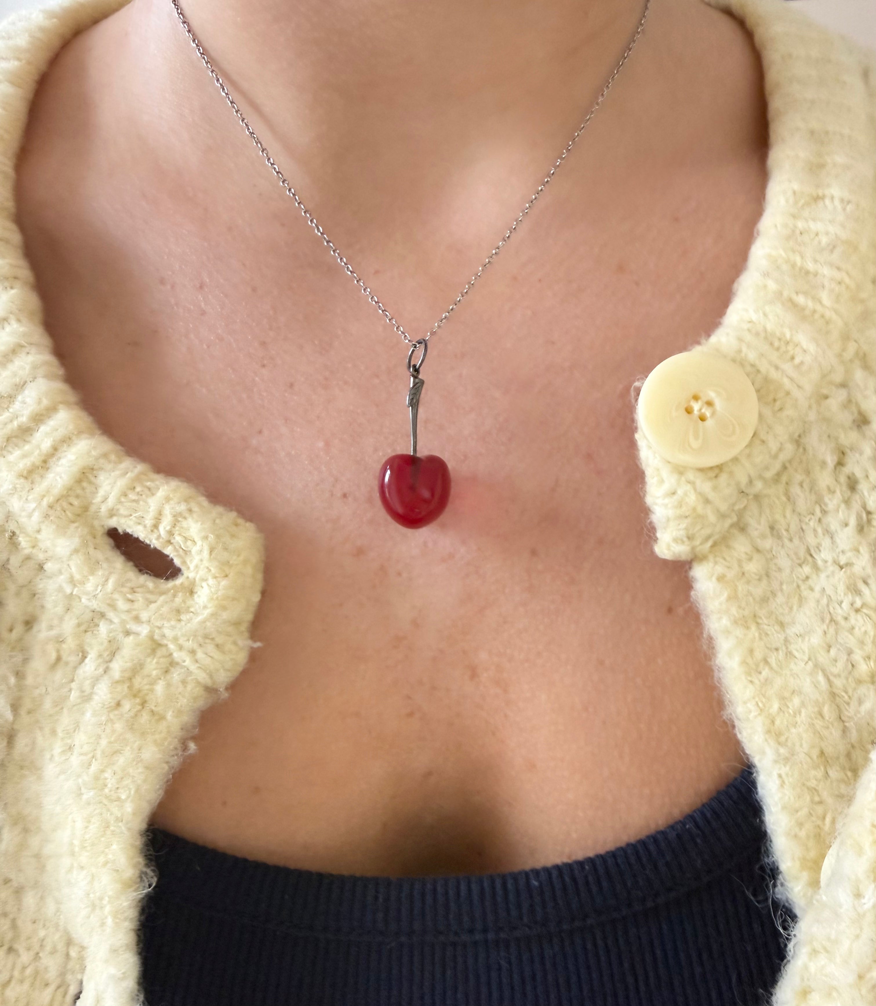 Model wearing red cherry charm with a silver stem on a silver chain. Designed by Maura Green.