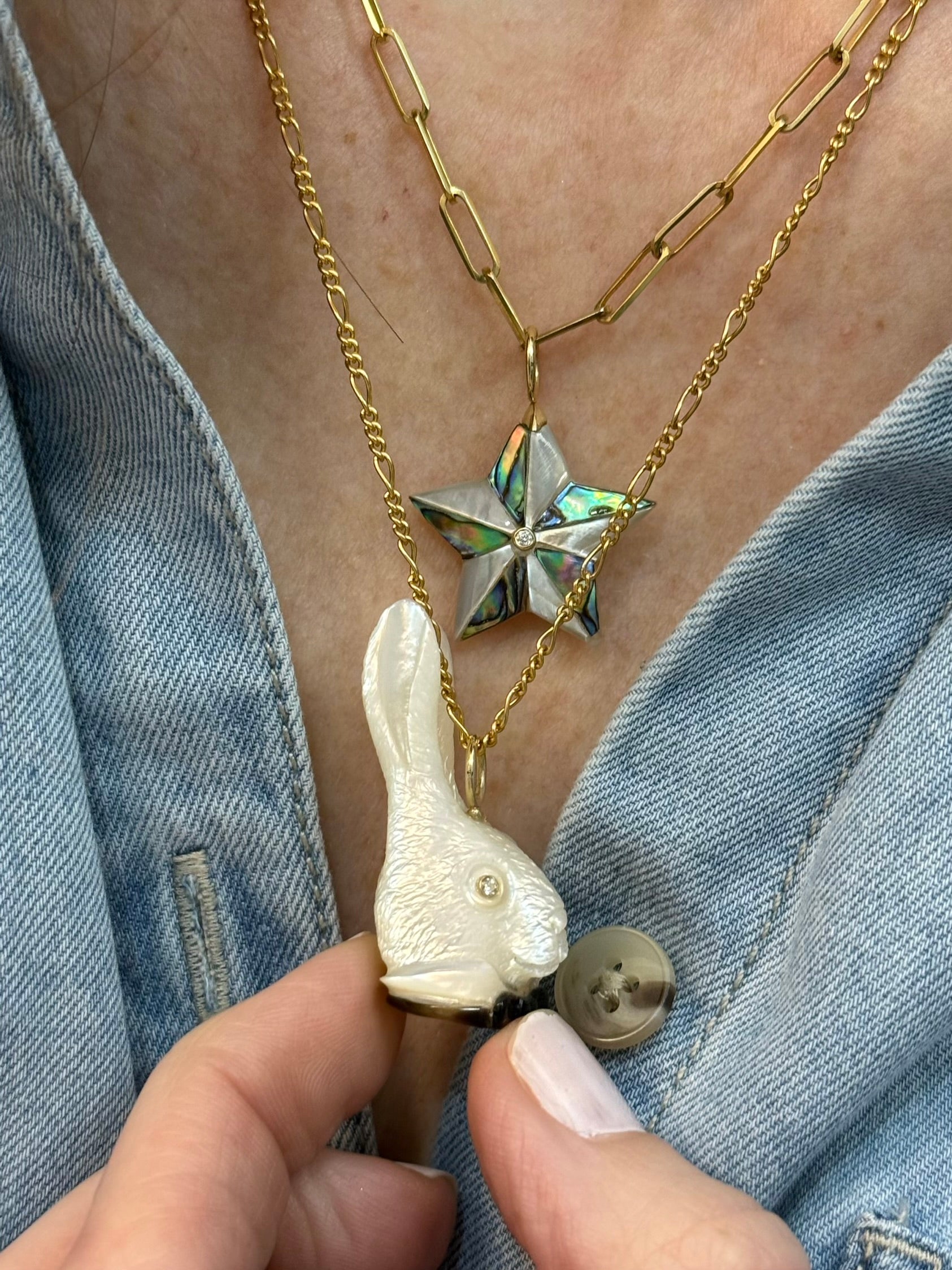 White rabbit head charm with a black bowtie and diamond eyes on a model. Designed by Maura Green