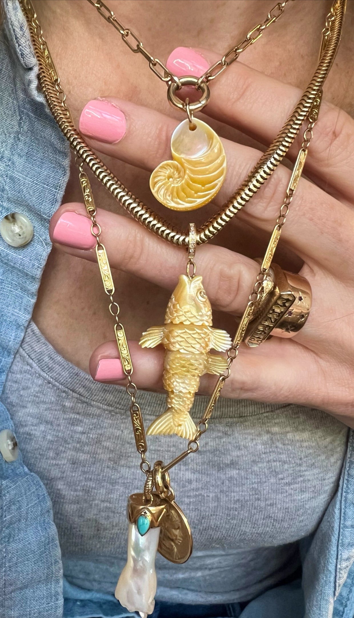 Gold fish-shaped charm with a gold chain on model's neck designed by Maura Green