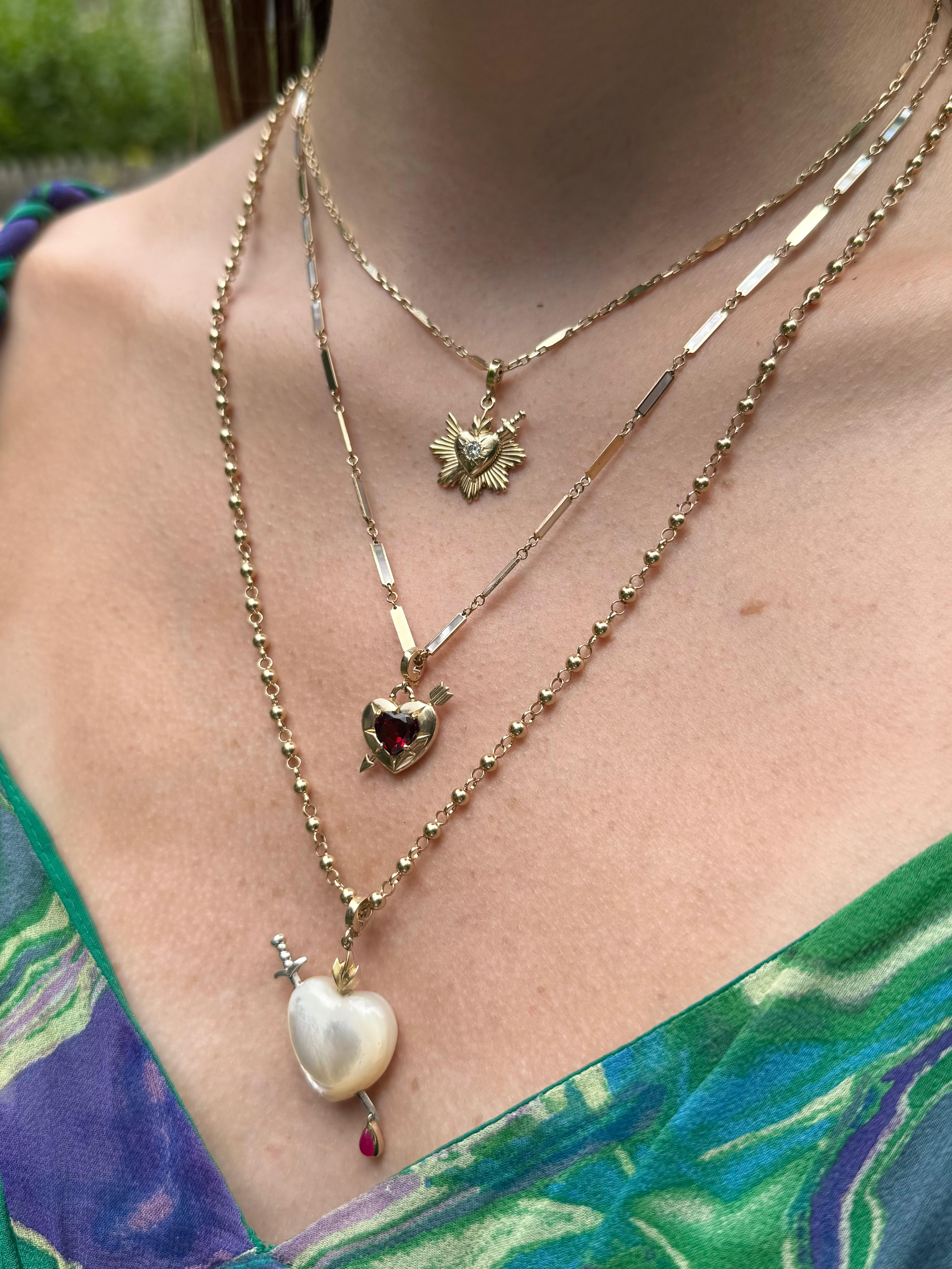 Necklace stack featuring Sacred Heart charm on a gold chain. Designed by Maura Green