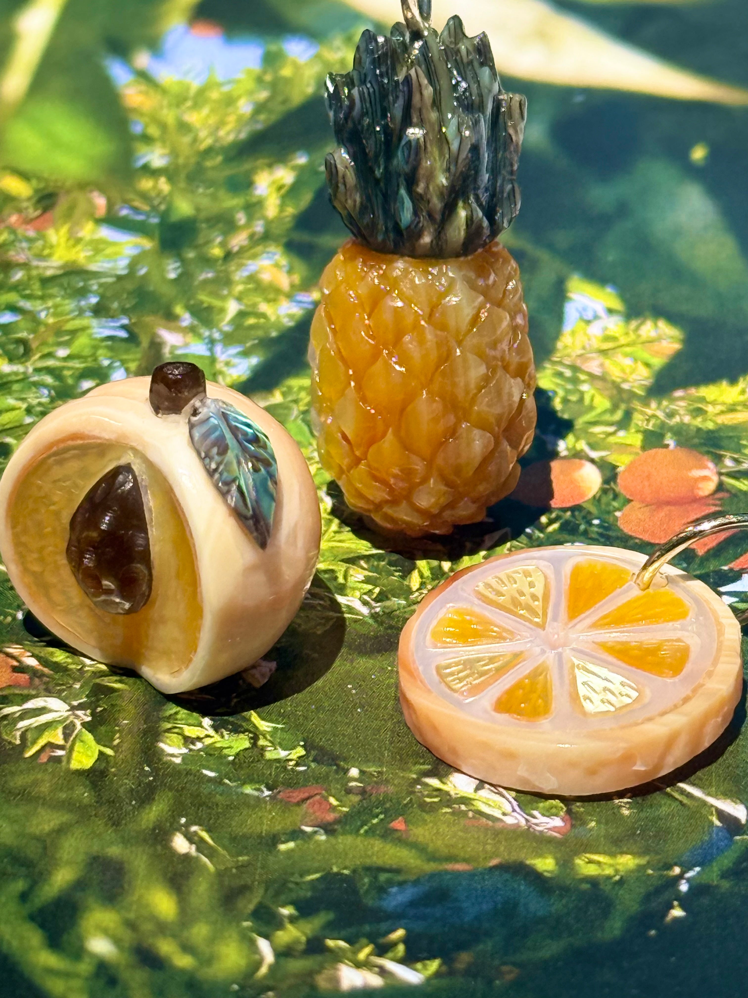 Peach, Pineapple, and orange slice charms on a green colorful background, designed by maura green