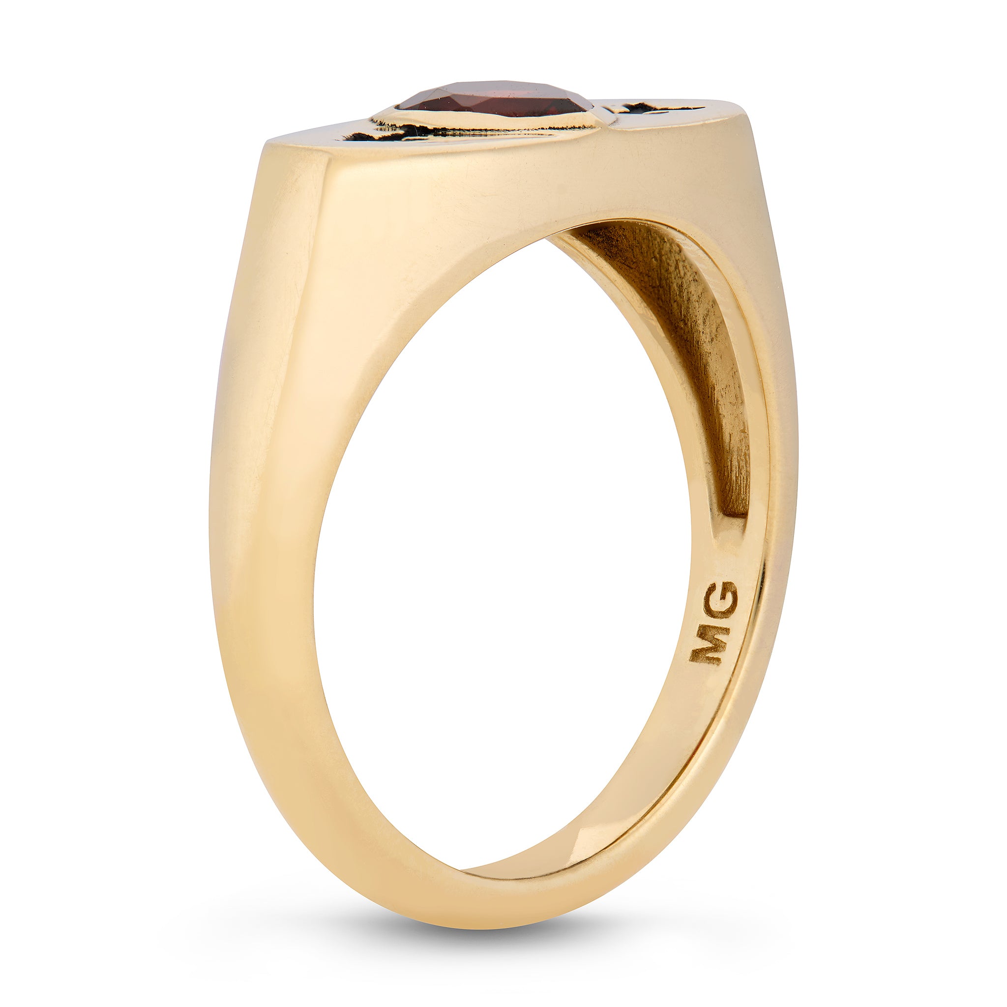 Gold ring with a red garnet on a white background designed by maura green