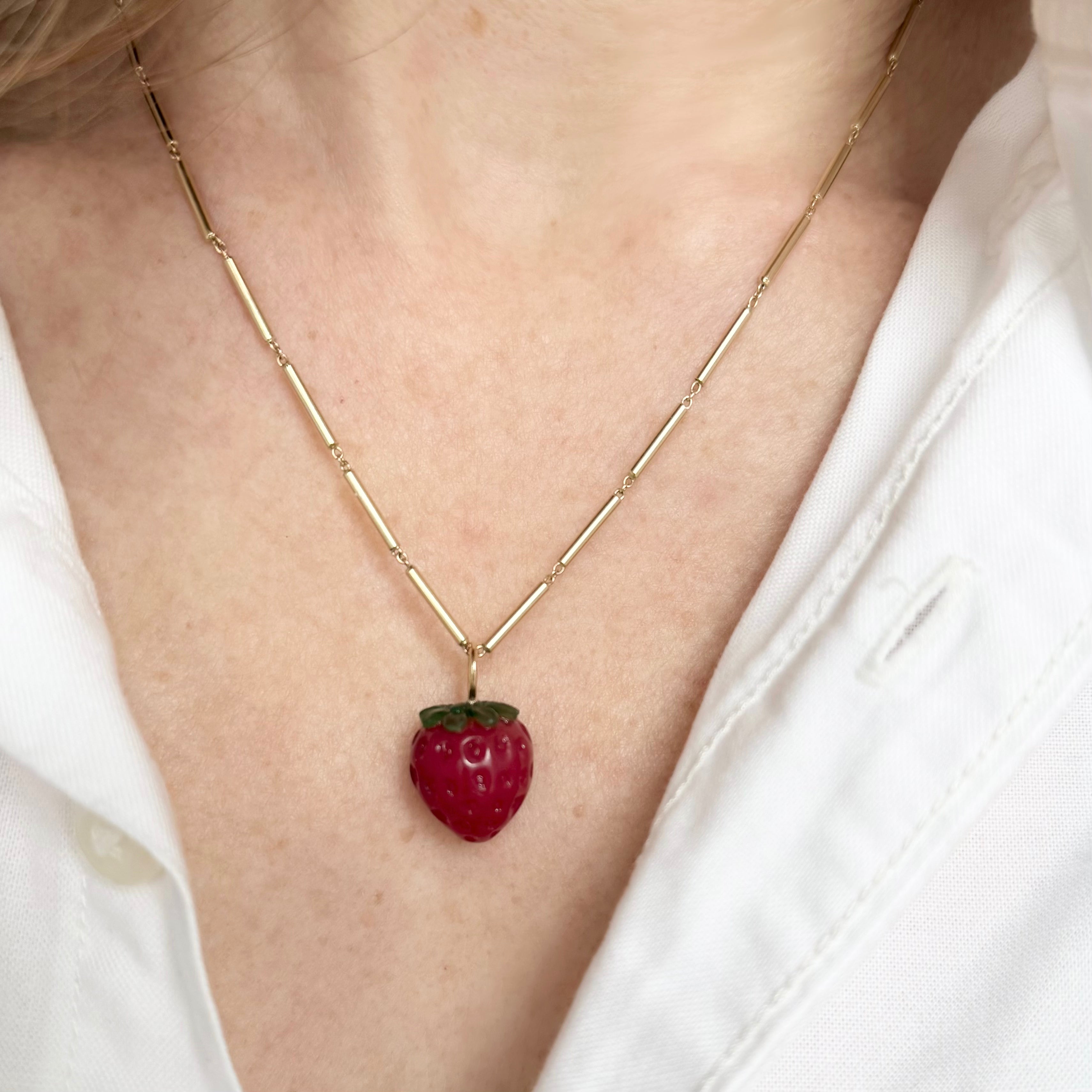 Necklace with a strawberry charm on a gold chain worn by a model. Designed by Maura Green